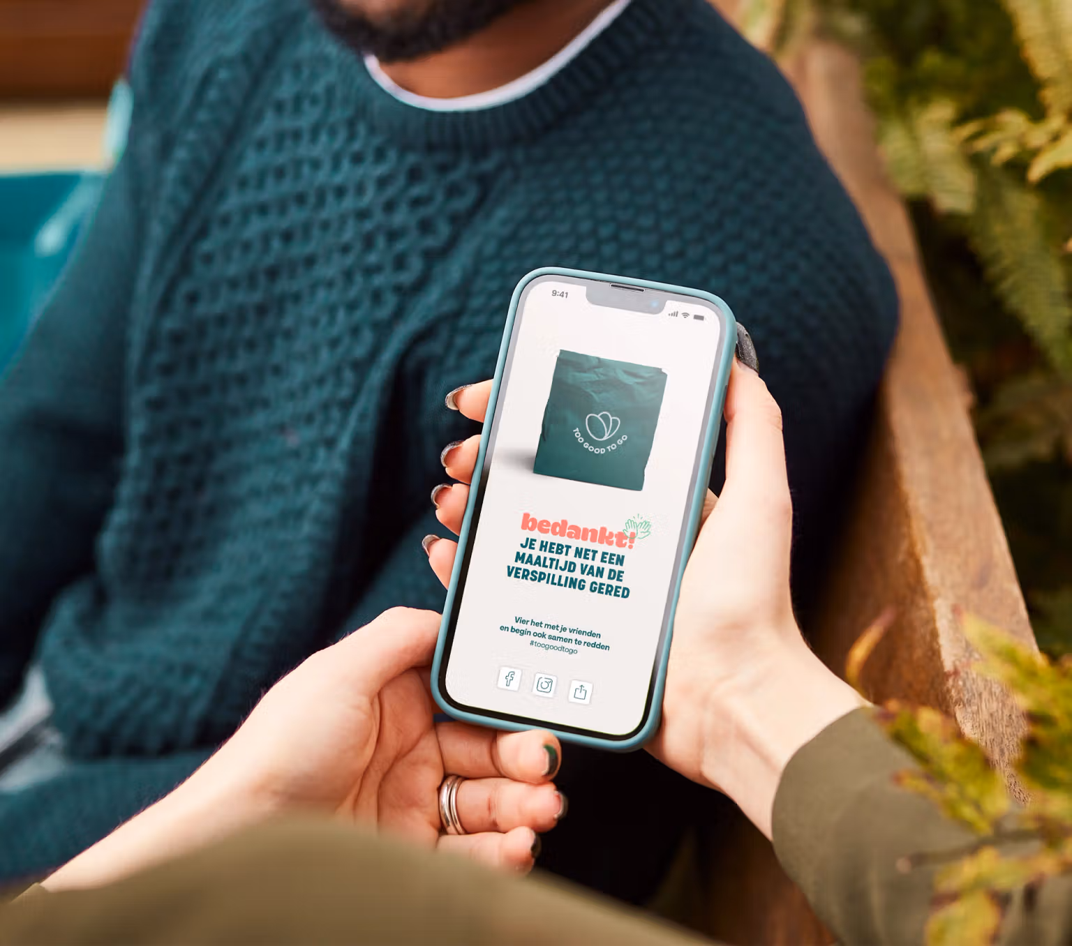 a woman is holding a cell phone in front of a man.
